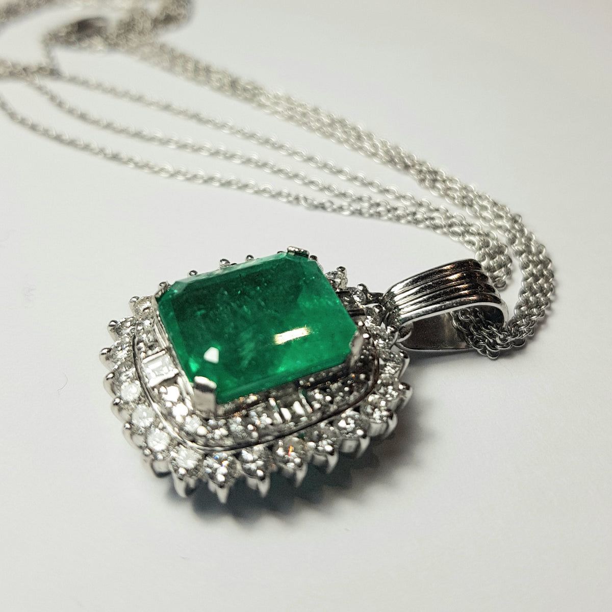 Pendente in platino con smeraldo naturale ct. 7,92 e diamanti naturali per ct. 1,57 totali completo di catenina a 3 fili in oro bianco 18k
