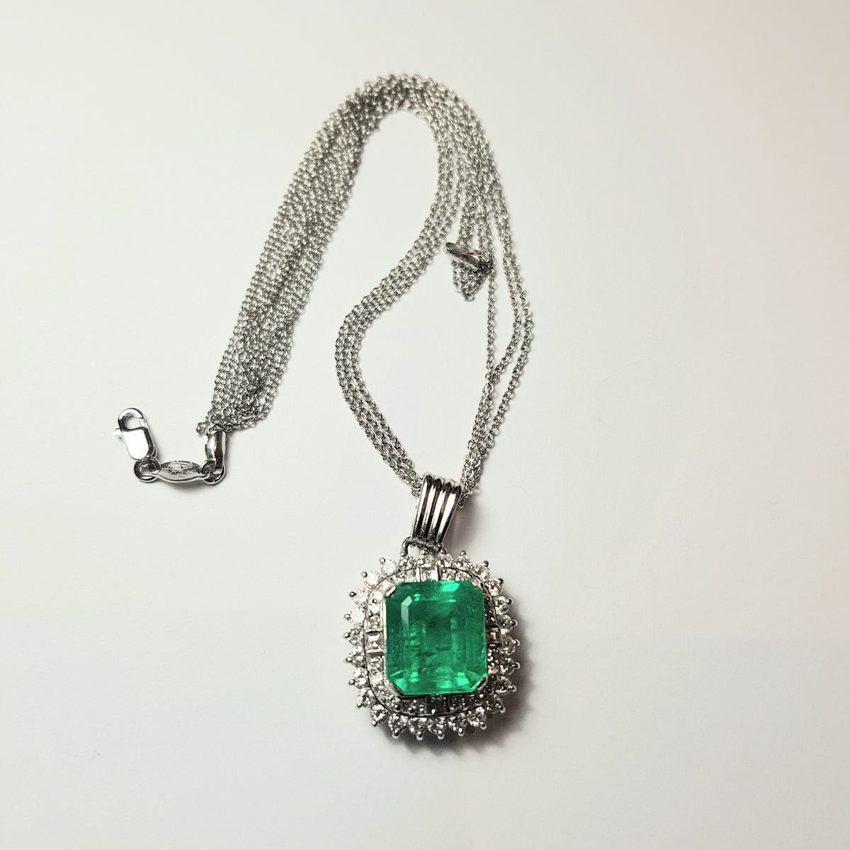Pendente in platino con smeraldo naturale ct. 7,92 e diamanti naturali per ct. 1,57 totali completo di catenina a 3 fili in oro bianco 18k
