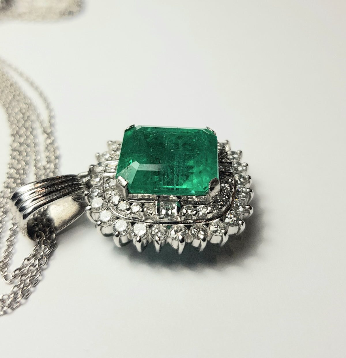 Pendente in platino con smeraldo naturale ct. 7,92 e diamanti naturali per ct. 1,57 totali completo di catenina a 3 fili in oro bianco 18k